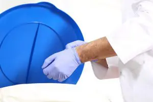 Zdravnik slači modre nitril rokavice in jih meče v koš