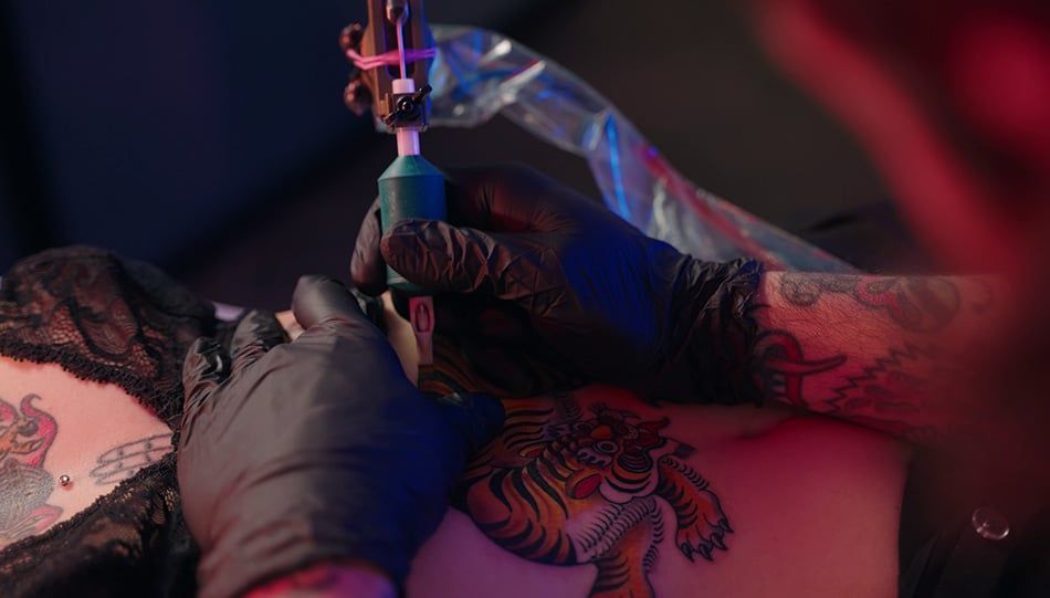 Tetovator dela tattoo in nosi črne rokavice iz nitrila
