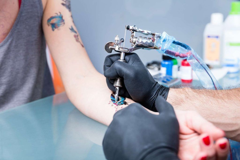Tetovator s črnimi rokavicami iz nitrila dela tattoo