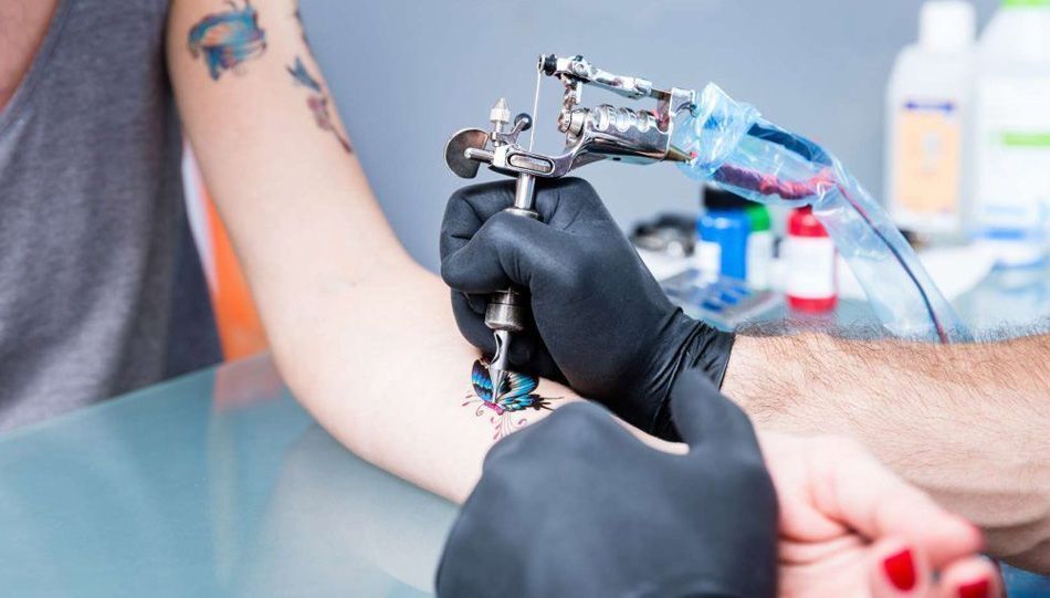 Tetovator pri delanju tattooja uporablja črne nitril rokavice za enkratno uporabo.